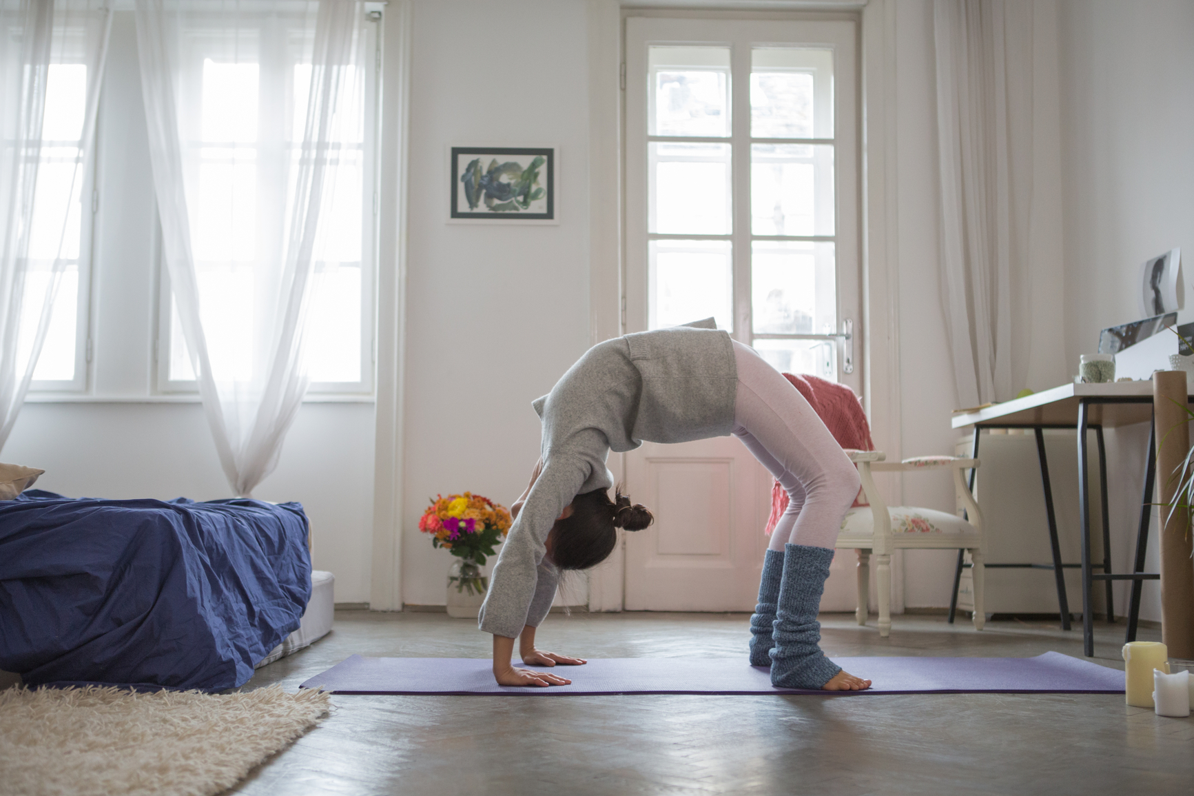 Yoga at home: woman doing the Wheel pose (Urdhva Dhanurasana)